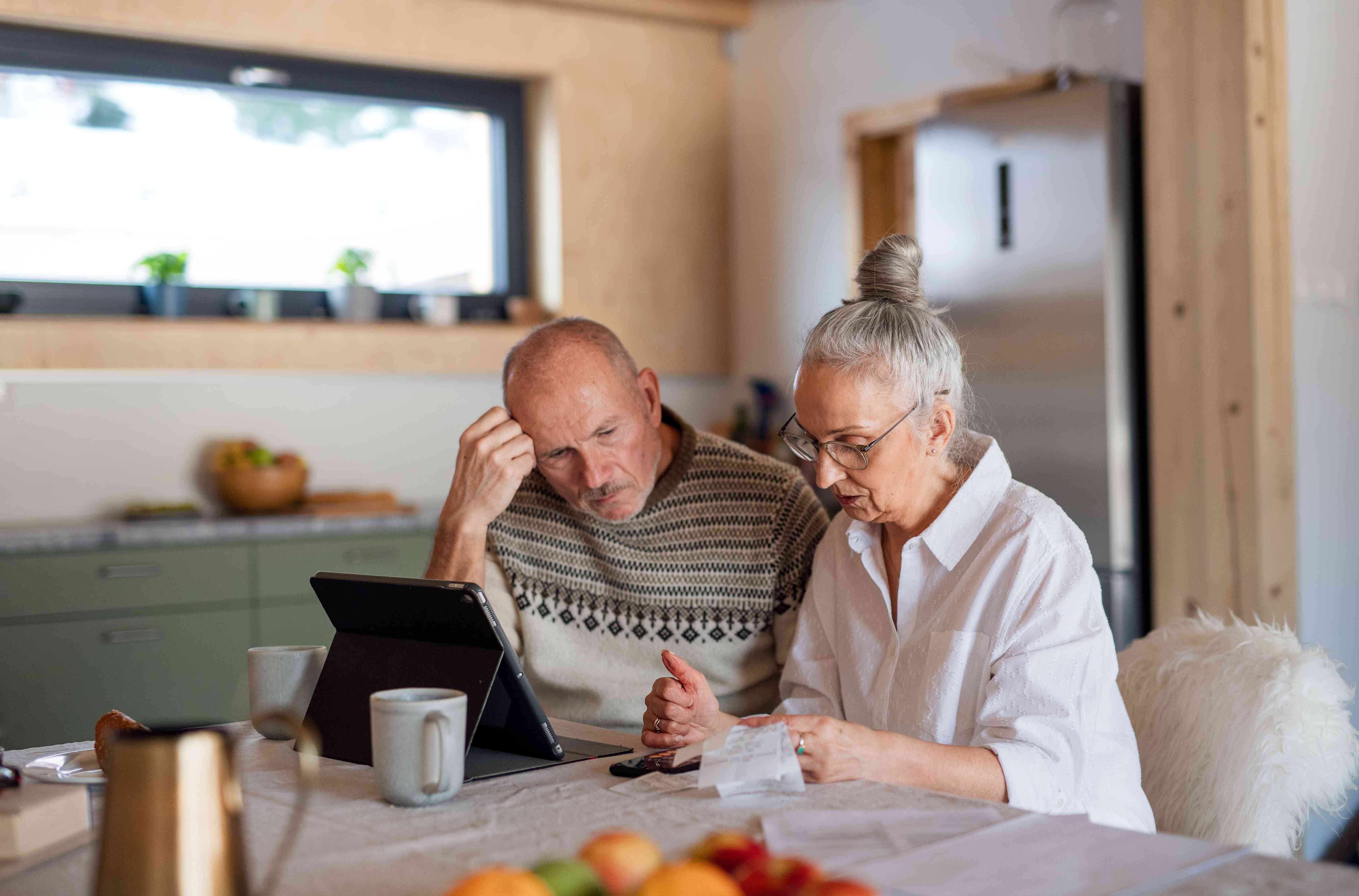 Older couple sitting at table with laptop and papers