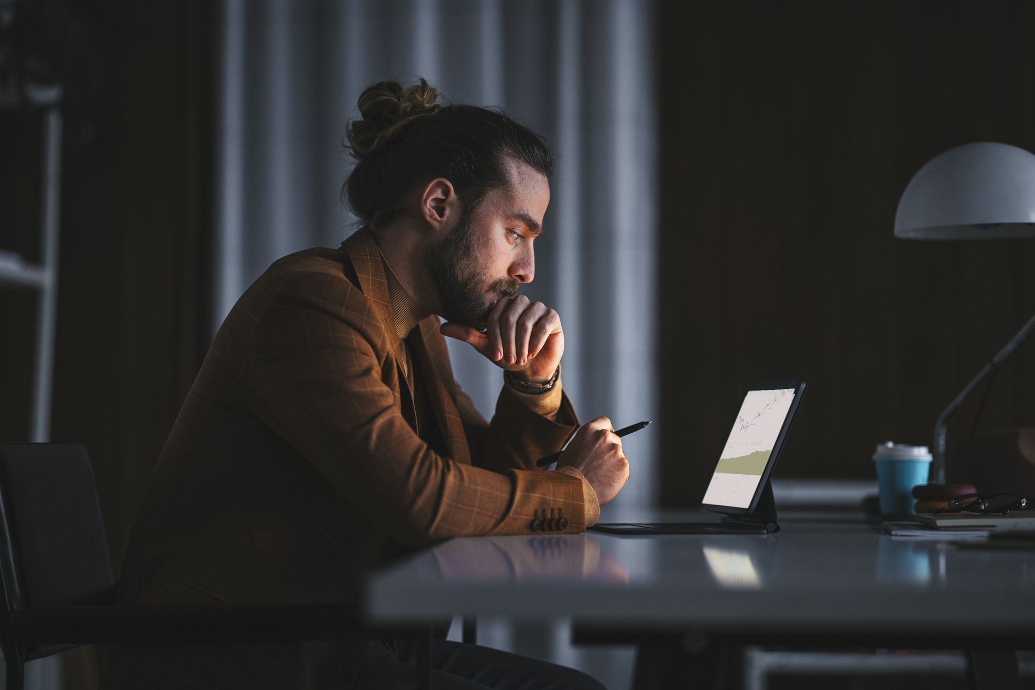 A man looks at his mutual funds investments on his tablet while at home at night