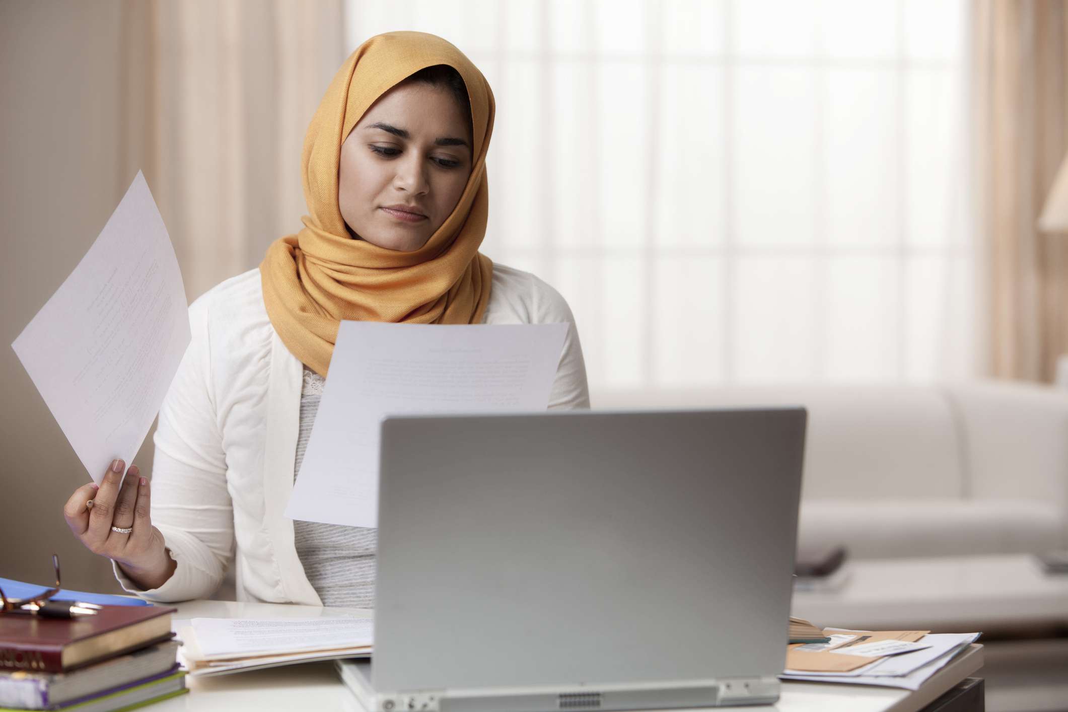 Person looking through paperwork, using a laptop