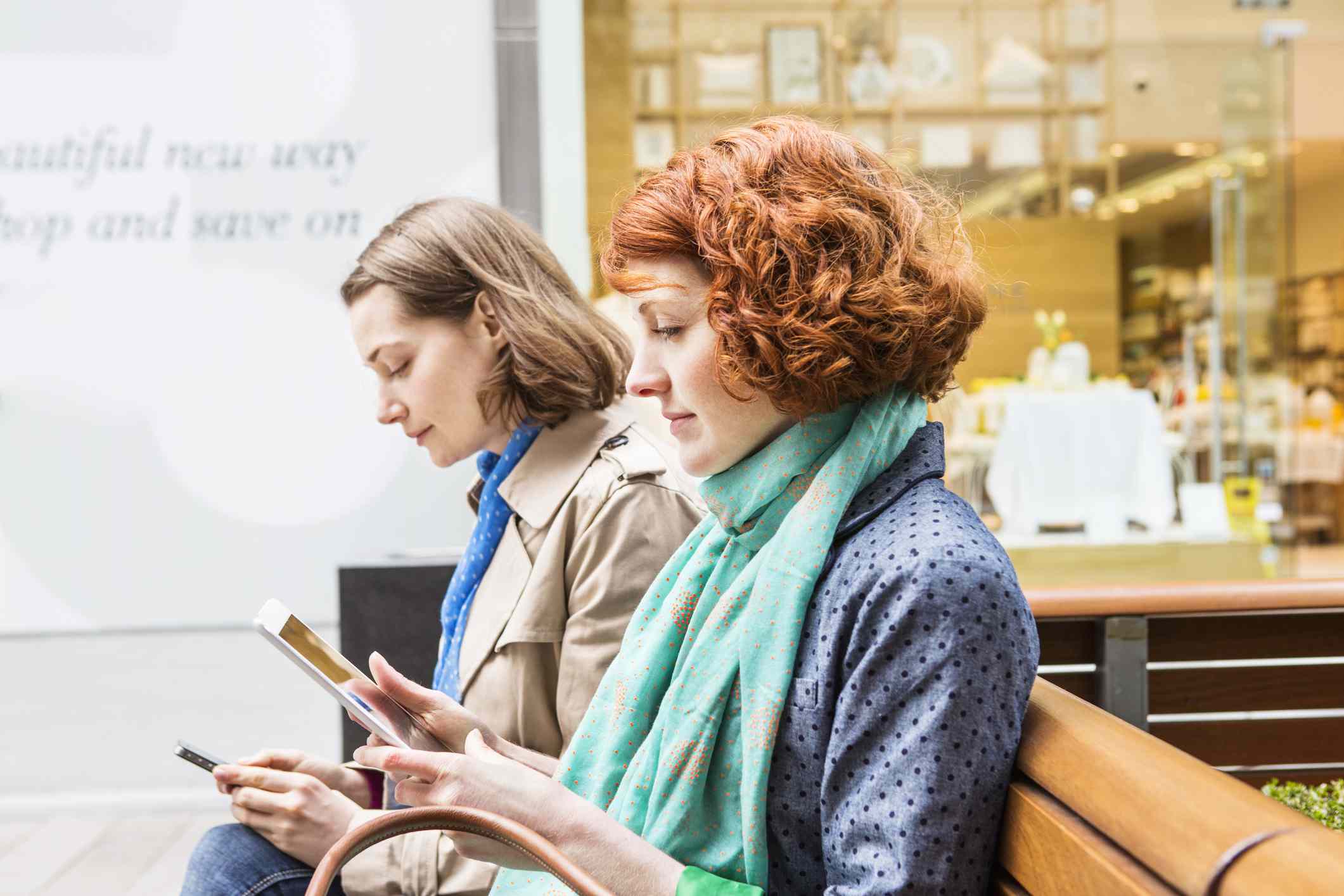 Women sitting in shopping area looking at internet