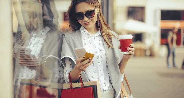 Woman holding a cup of coffee and shopping bags