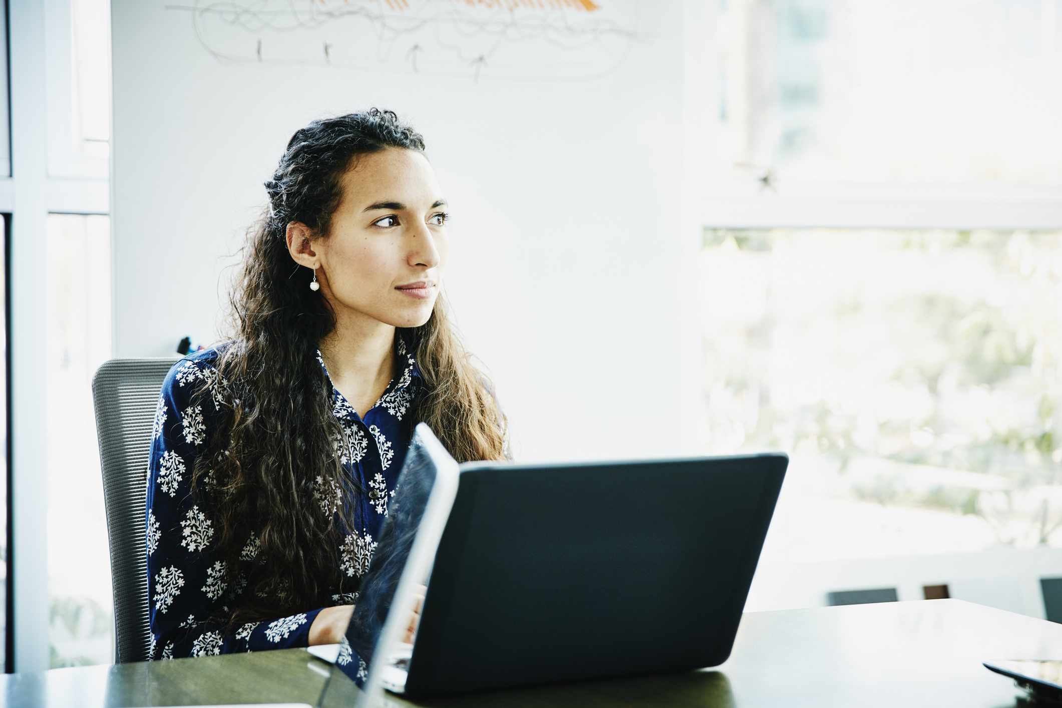 A woman sits at a desk with a computer.