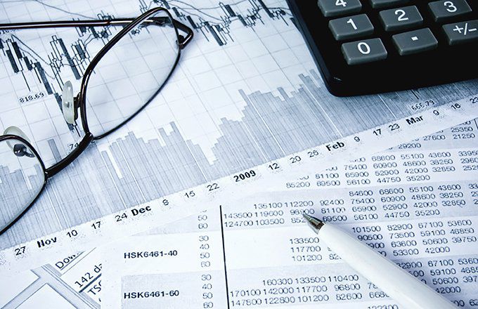 Close-up of financial papers with glasses, pen, and calculator