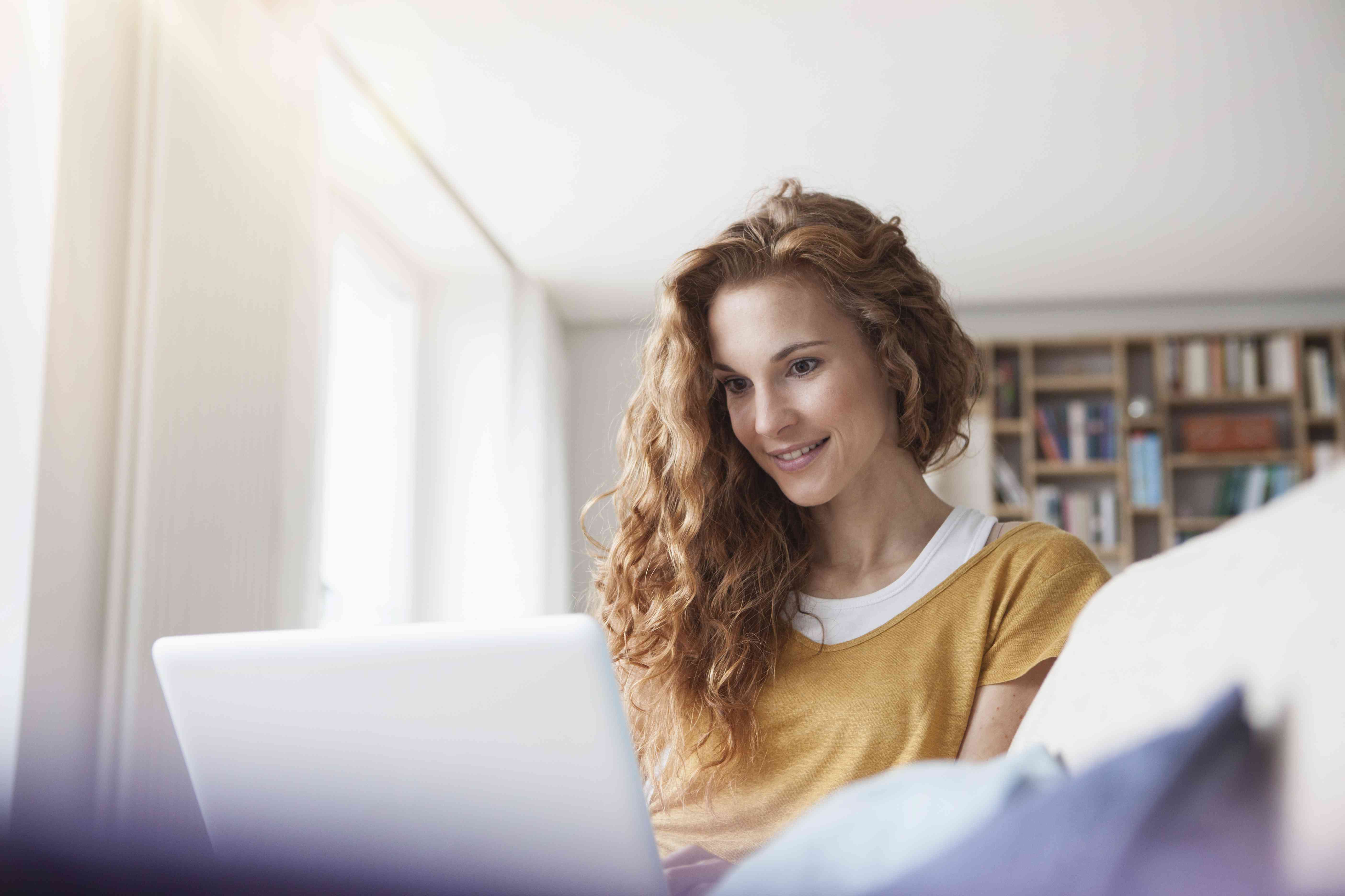 A woman using a laptop in a home setting.