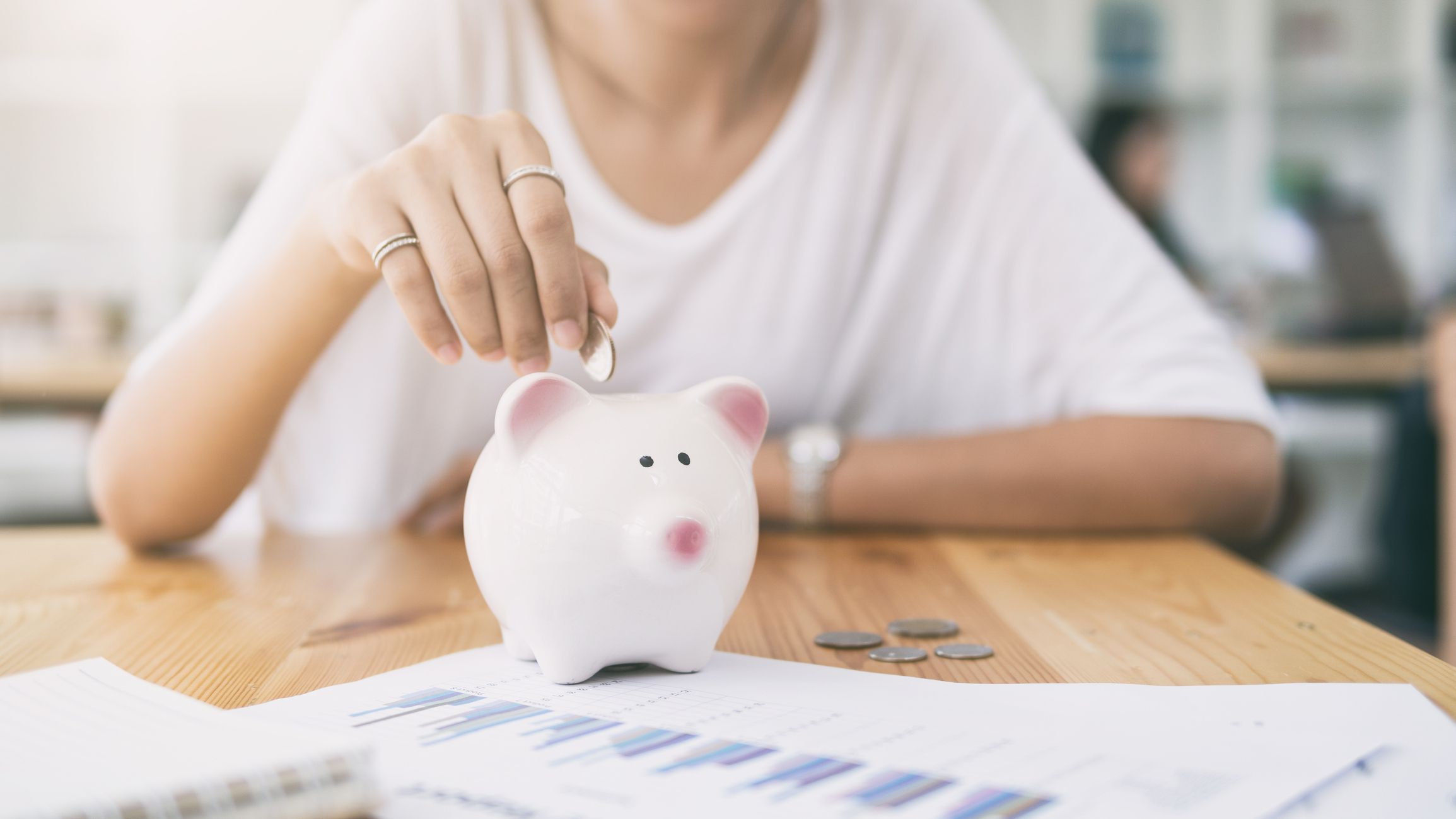 Woman dropping coin in piggy bank